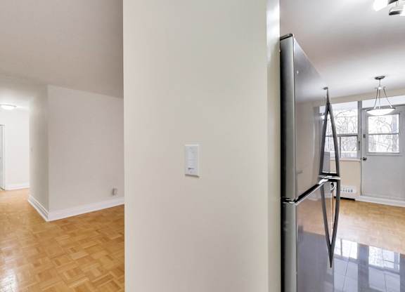 A kitchen with a refrigerator and a wooden floor.