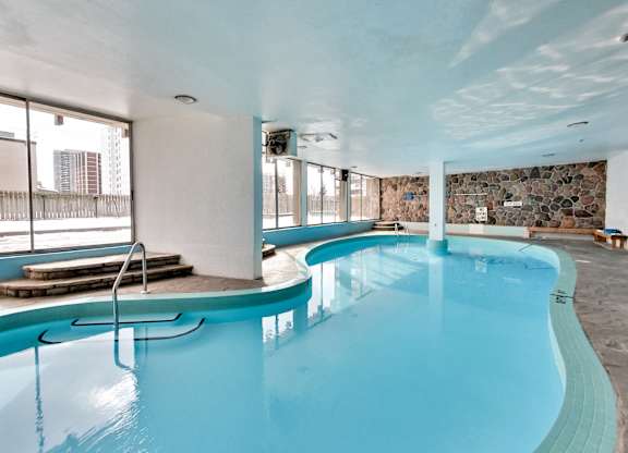 an indoor pool with blue water and a wall of windows