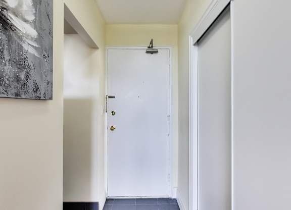 A white door with a black handle is in a hallway.