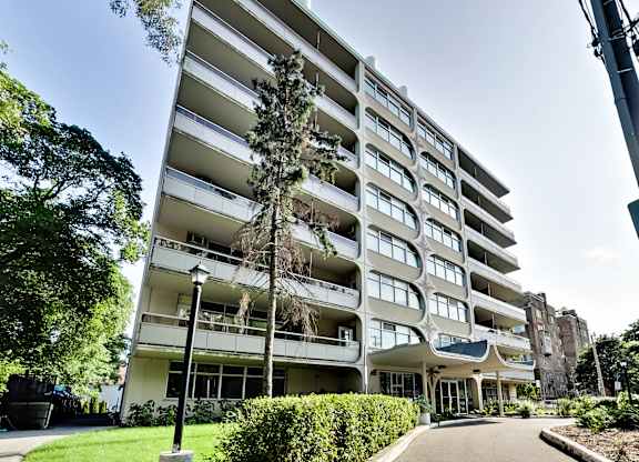 A tall white apartment building with balconies and a green lawn in front.