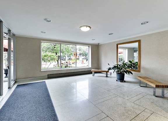 an empty living room with a large window and a potted plant