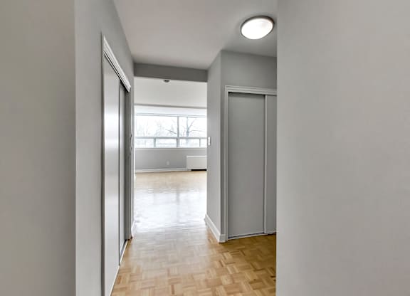 an empty living room with a window and a door to a bedroom