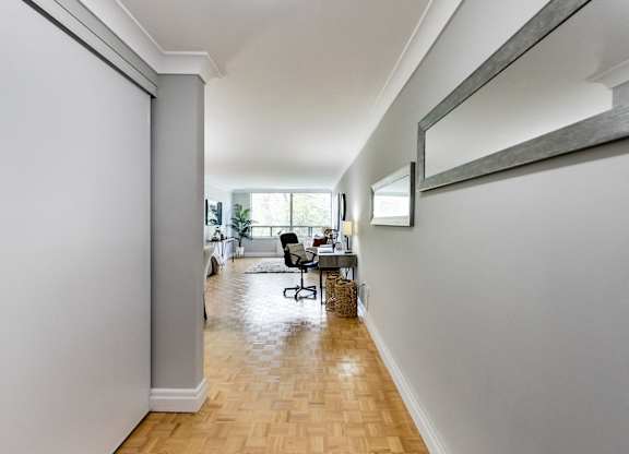 A long hallway with a chair and a mirror on the wall.
