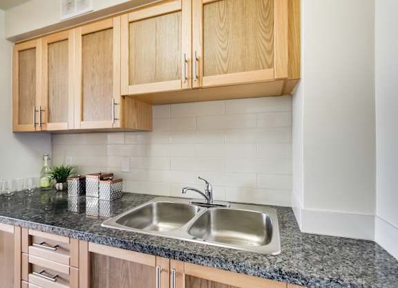 A kitchen with a granite countertop and wooden cabinets.
