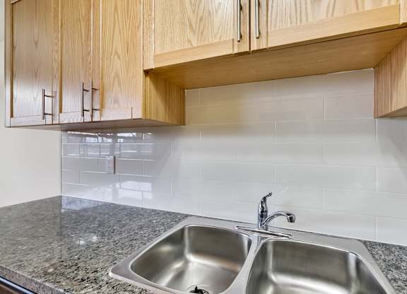 A kitchen with a granite countertop and a double sink.
