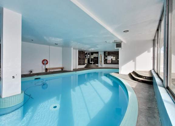 a swimming pool in the middle of a room with a kitchen and a large window