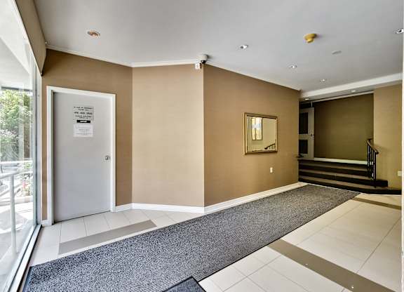 a lobby with a door and a carpeted floor and a staircase