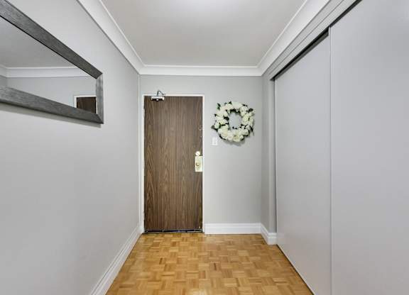 A hallway with a wooden door and a wreath on the wall.