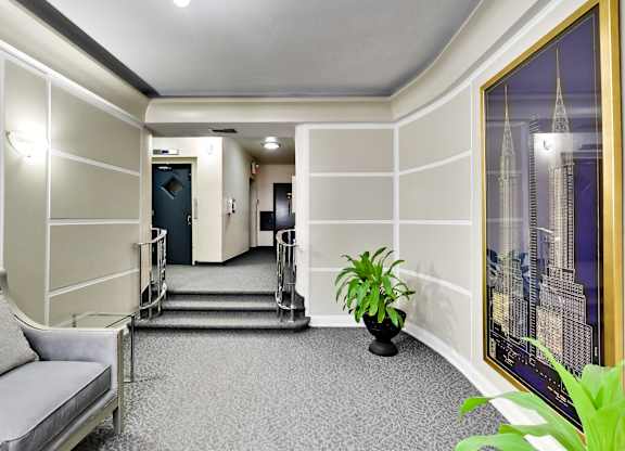 a lobby of a hotel with a plant and a staircase