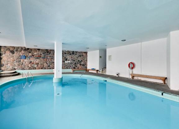 a swimming pool with blue water and a stone wall