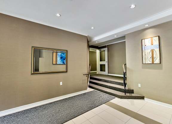 a entryway with carpet and stairs and a mirror on the wall