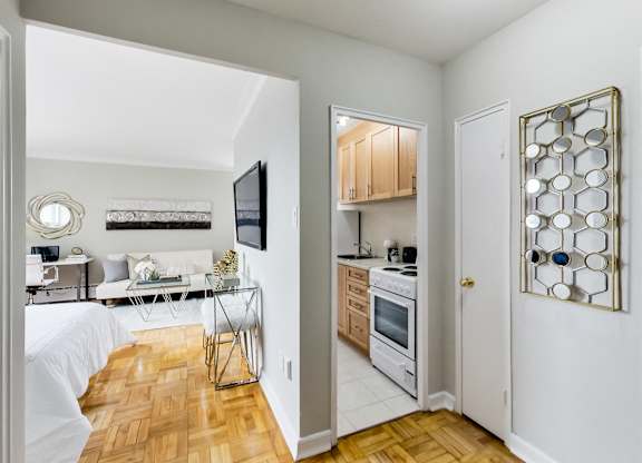 a bedroom with a bed and a living room with a desk and a kitchen
