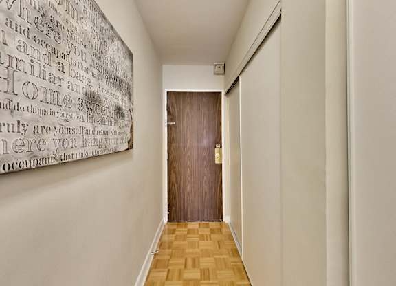 A hallway with a wooden floor and a wall with a word cloud on it.