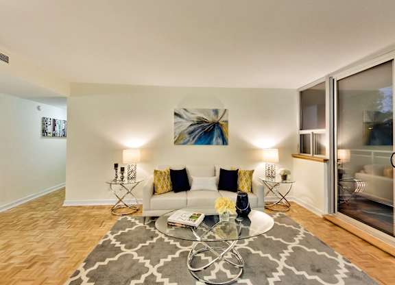 A living room with a white couch and a grey rug.