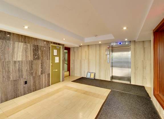 A hallway with a wooden floor and a grey carpet.
