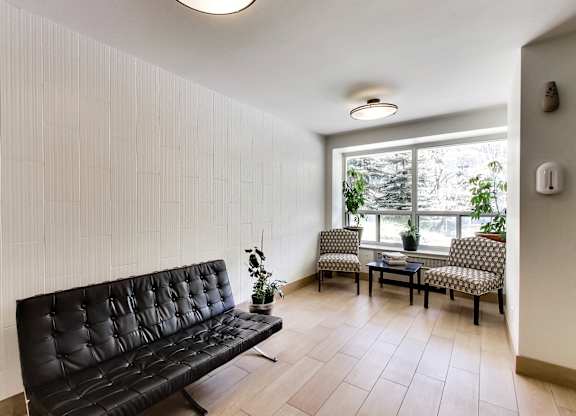 a living room with black leather furniture and a large window