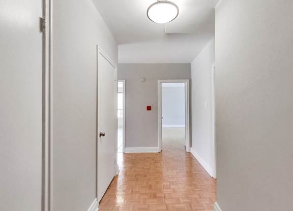 an empty hallway with white walls and a wood floor