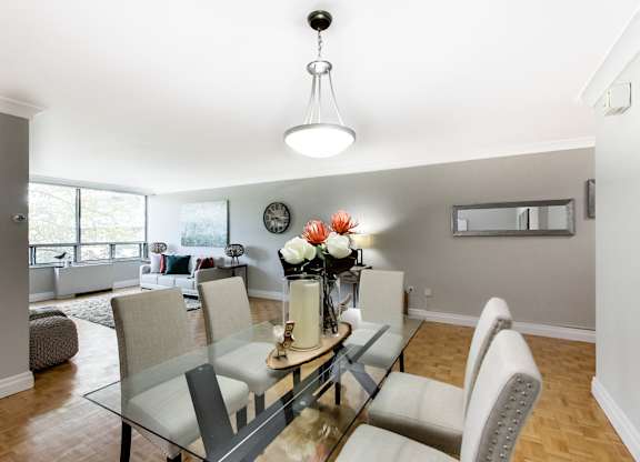 A modern dining room with a glass table and chairs.