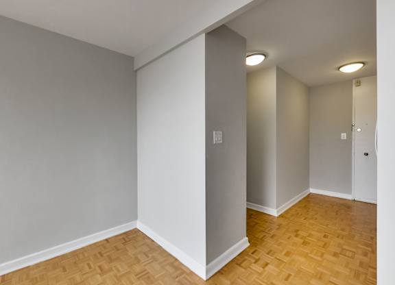 an empty living room with wood flooring and grey walls