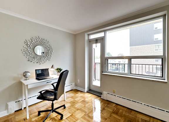 a home office with a desk and a laptop and a large window