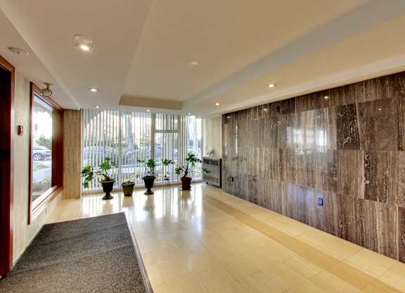 A hallway with a brown marble wall and a grey carpet.