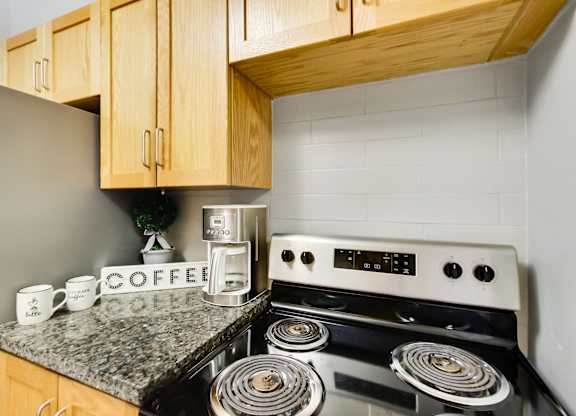 A coffee maker is on a counter next to a stove.