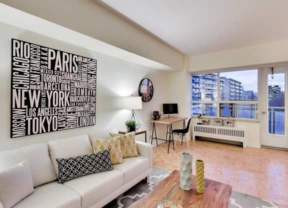 A living room with a white couch and a word art on the wall.