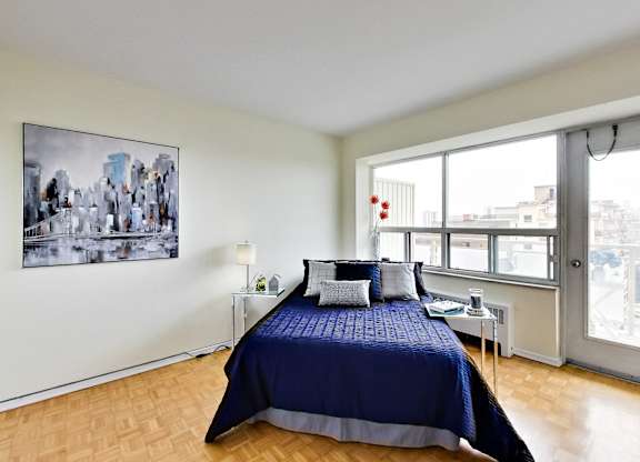 A bedroom with a large bed and a cityscape picture on the wall.