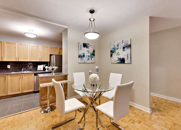 a dining room with a glass table and chairs and a kitchen