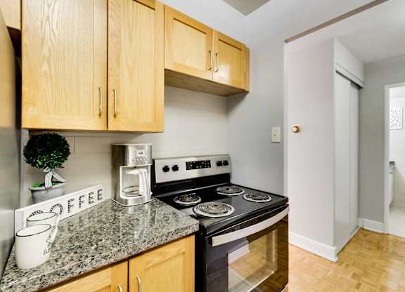 A kitchen with a stove top oven and wooden cabinets.