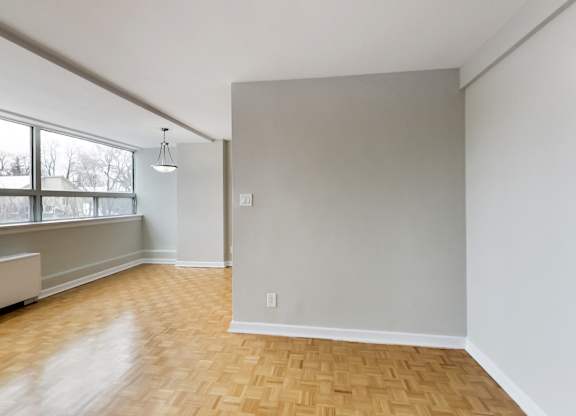 an empty living room with wood floors and a large window