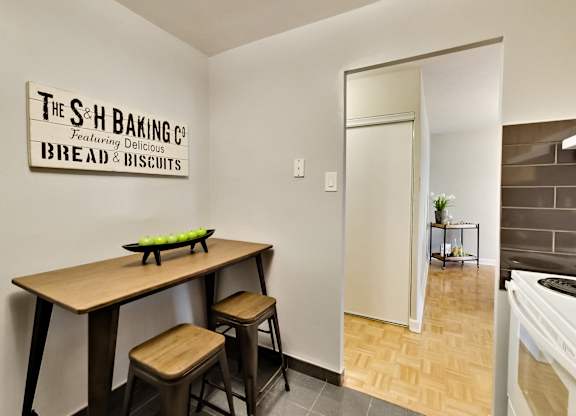A bakery with a wooden table and stools is set up in a room.