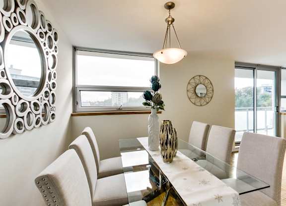 A modern dining room with a glass table and chairs.
