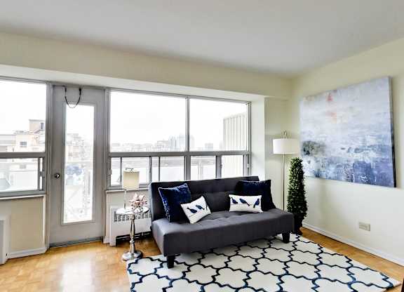 A living room with a grey couch and a large painting on the wall.