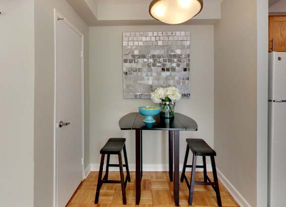 a small kitchen with a table and stools and a painting on the wall
