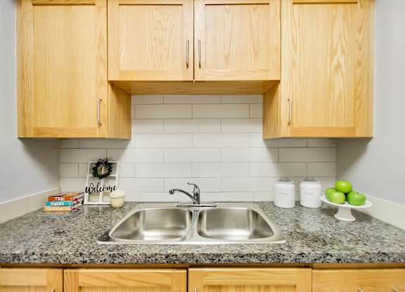 A kitchen with a granite countertop and wooden cabinets.