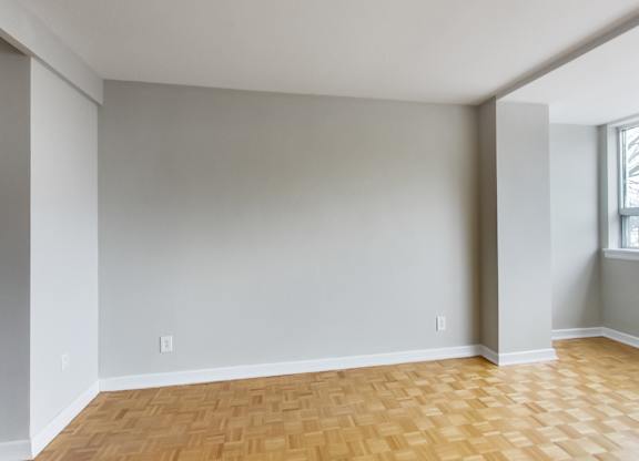 an empty living room with wood flooring and a window