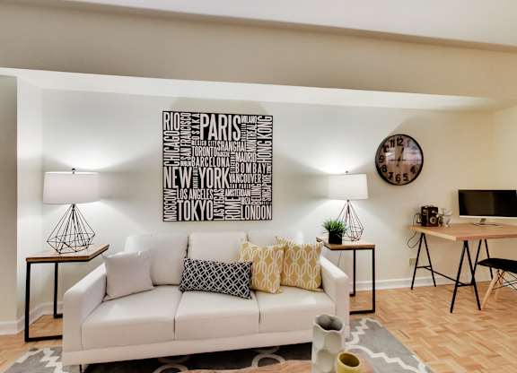 A white couch sits in front of a wall with a word art of cities.