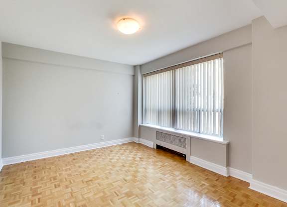 an empty living room with wood flooring and a large window