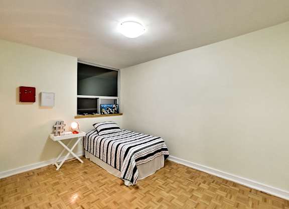 A bedroom with a bed, a table, and a window.