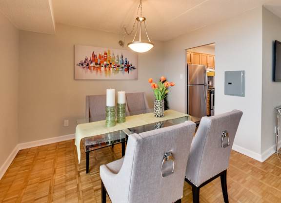 a dining room with a glass table and chairs and a kitchen with a refrigerator