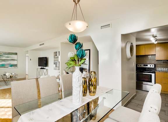 A modern dining room with a glass table and white chairs.