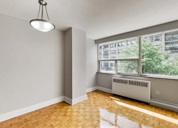 an empty living room with a large window and wood flooring