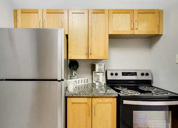 A kitchen with a stove, refrigerator, and cabinets.