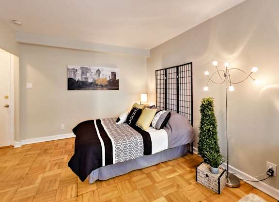 a bedroom with wood floors and a bed with a plant