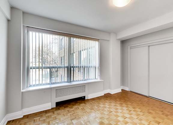 an empty living room with a large window and wood flooring