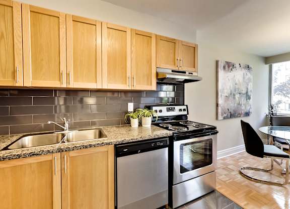 an apartment kitchen with stainless steel appliances and wooden cabinets