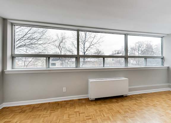 an empty living room with a large window and a radiator