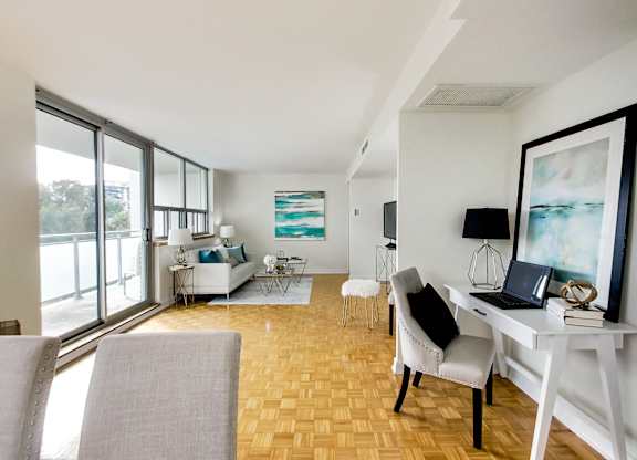 A room with a desk, chairs, and a painting on the wall.