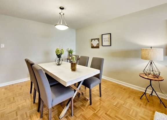 A dining room with a white table and grey chairs.